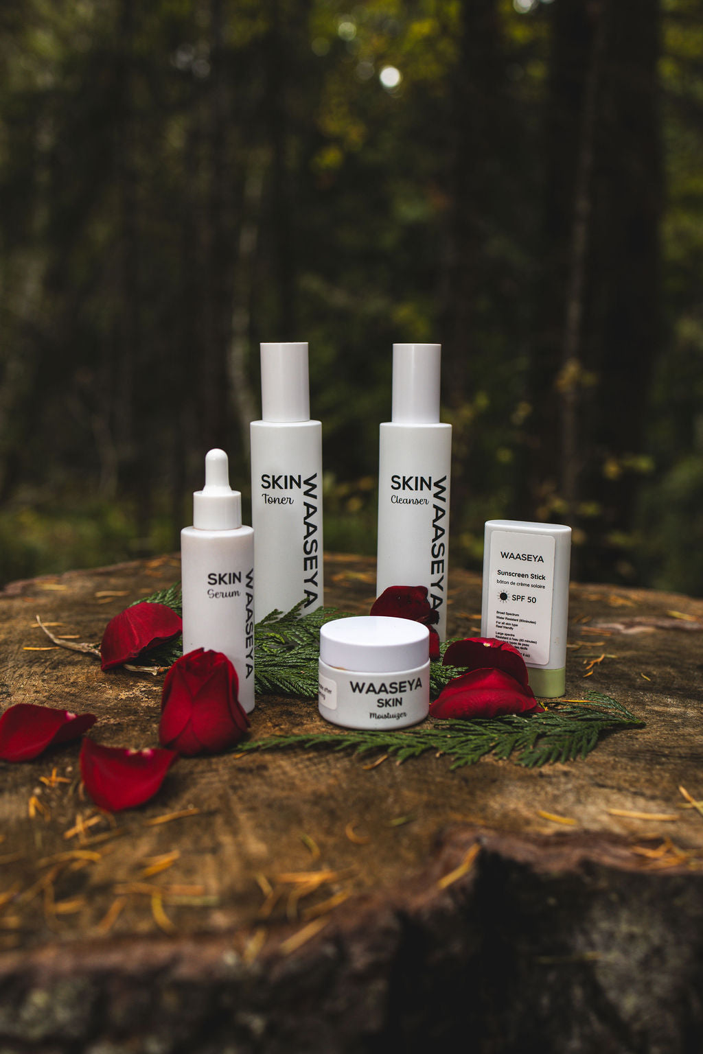 Waaseya skincare products on a wooden surface with red petals and green leaves against a blurred natural background