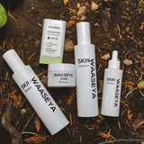 Set of Waaseya skincare products on a natural background with soil and leaves.