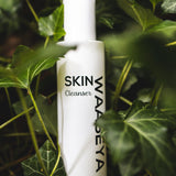 White bottle of SKIN WAASEYA Cleanser surrounded by green leaves