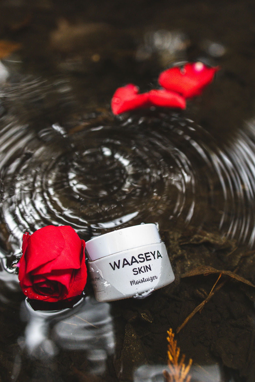 Waaseya facial moistuizer jar with red rose petals on water