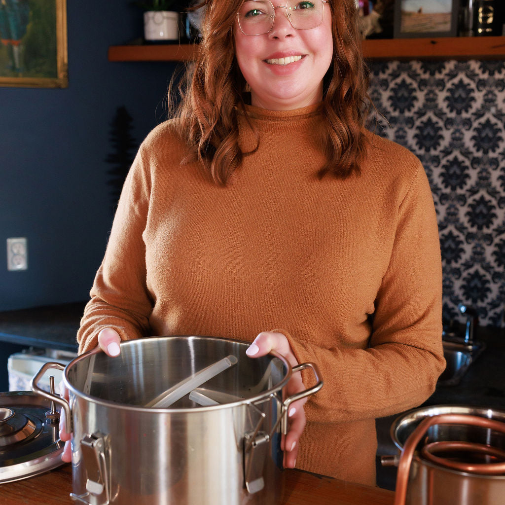 WAASEYA founder, Taylor,  holding a large metal pot in a kitchen setting